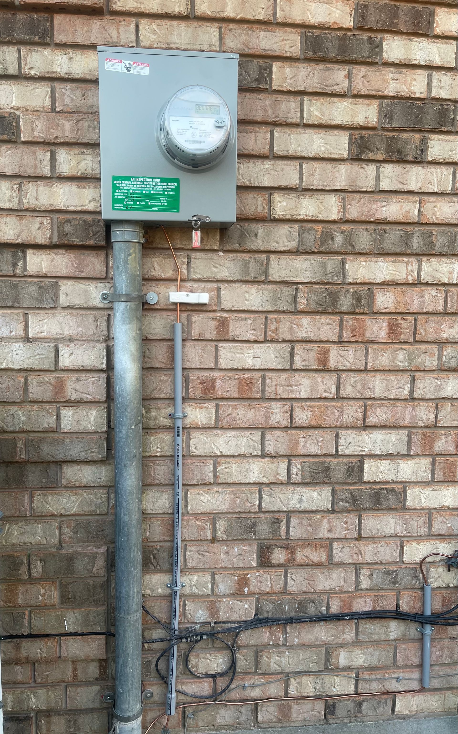 There is a meter on the side of a brick wall.