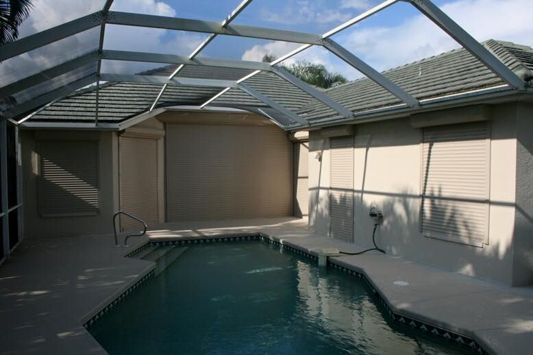 A screened in swimming pool in the backyard of a house
