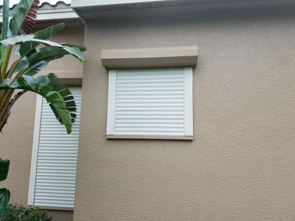a window with a roller shutter on a white brick wall .