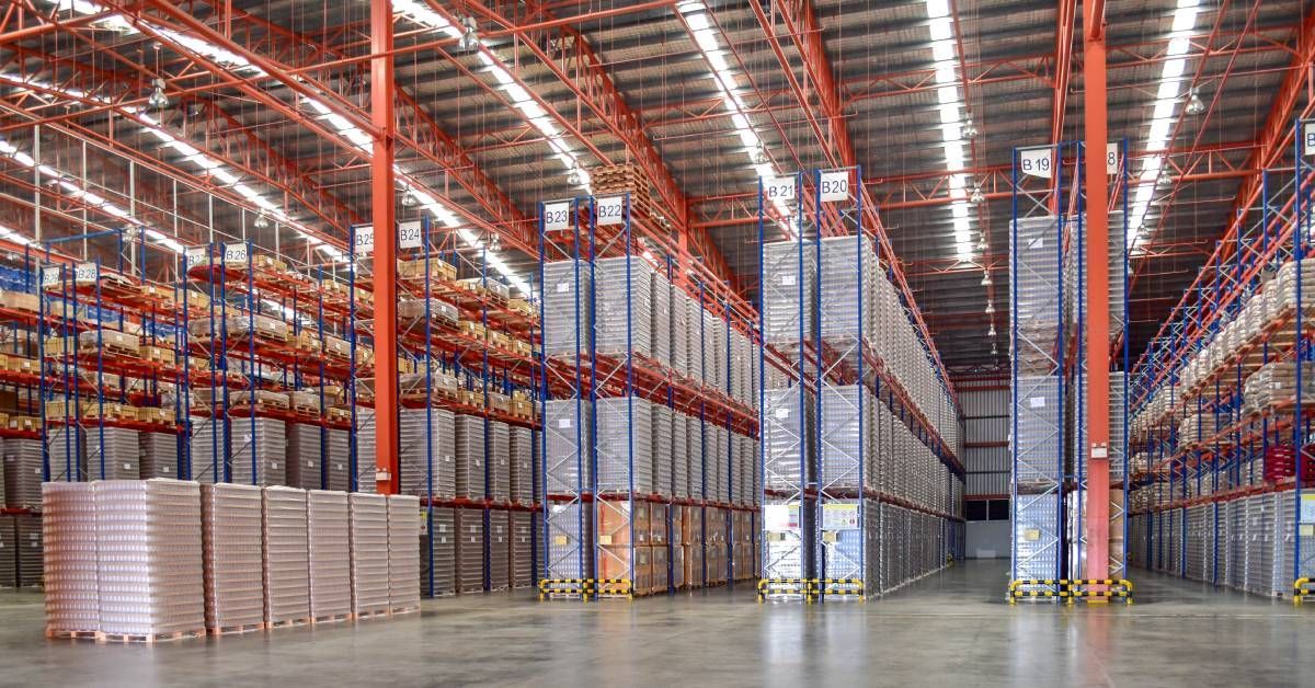 Multiple rows of floor-to-ceiling industrial steel shelving units in a large distribution warehouse space.