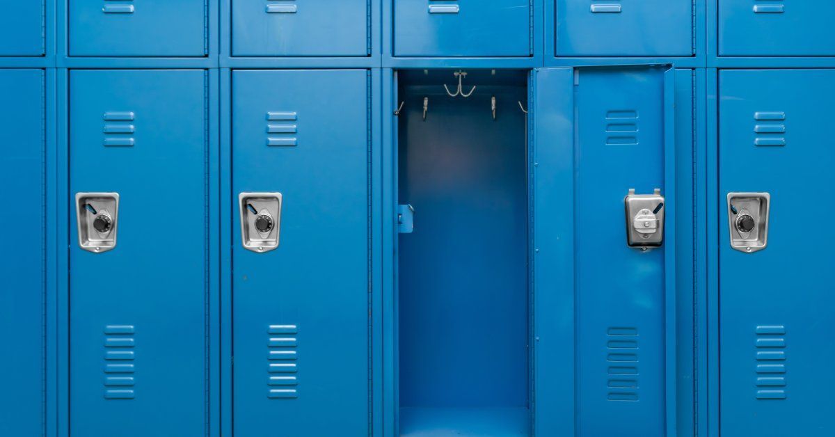 A close-up view of blue, double-stacked metal lockers with combination locks. All but one locker is locked and closed.