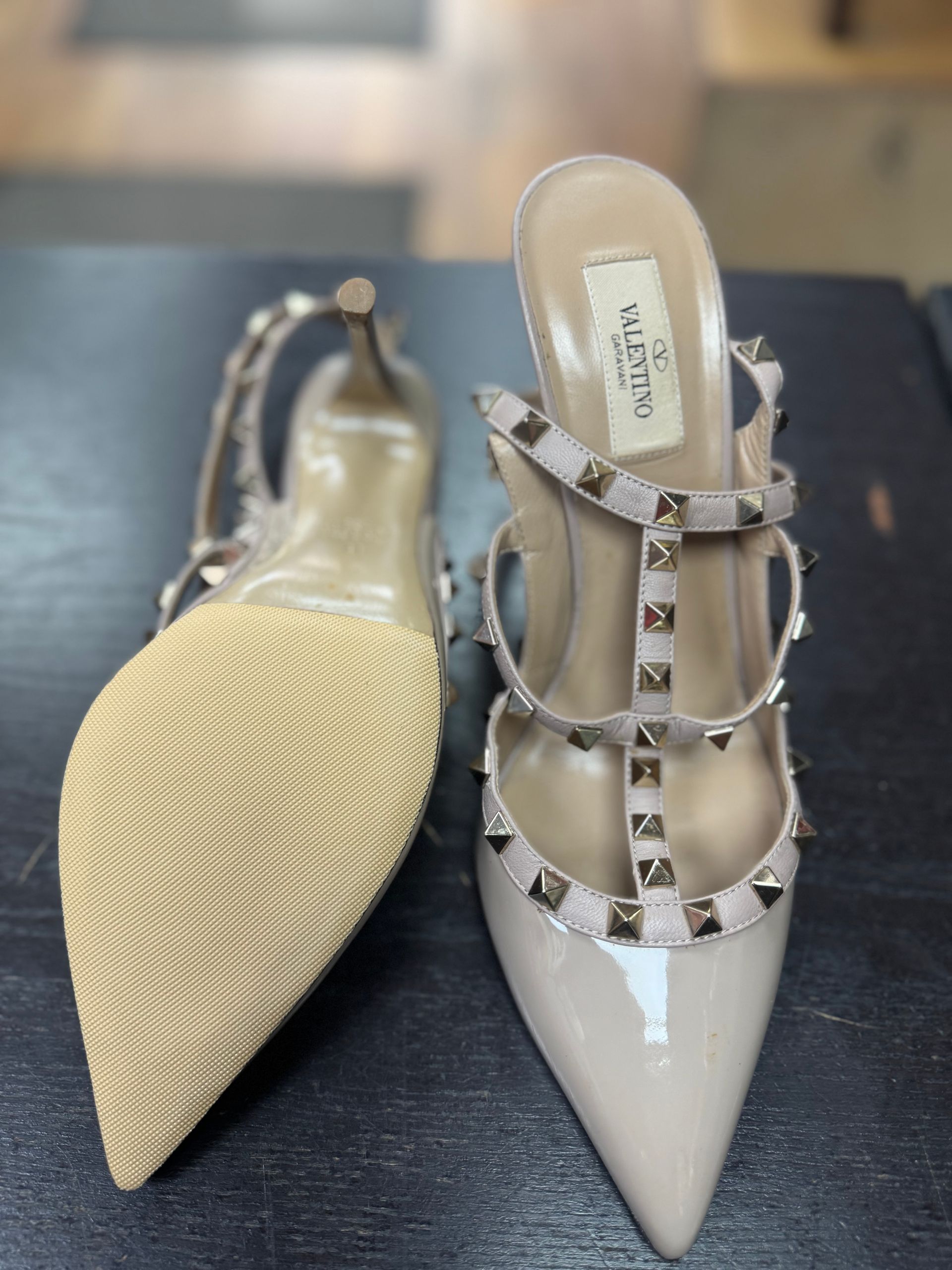 A pair of beige Valentino Rockstud stiletto heels, one showing the sole and one showing the studded T-strap design.