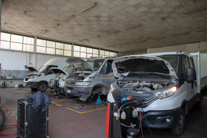 Veicoli con cofani aperti in un'officina. Reparto officina, con attrezzi e un compressore.