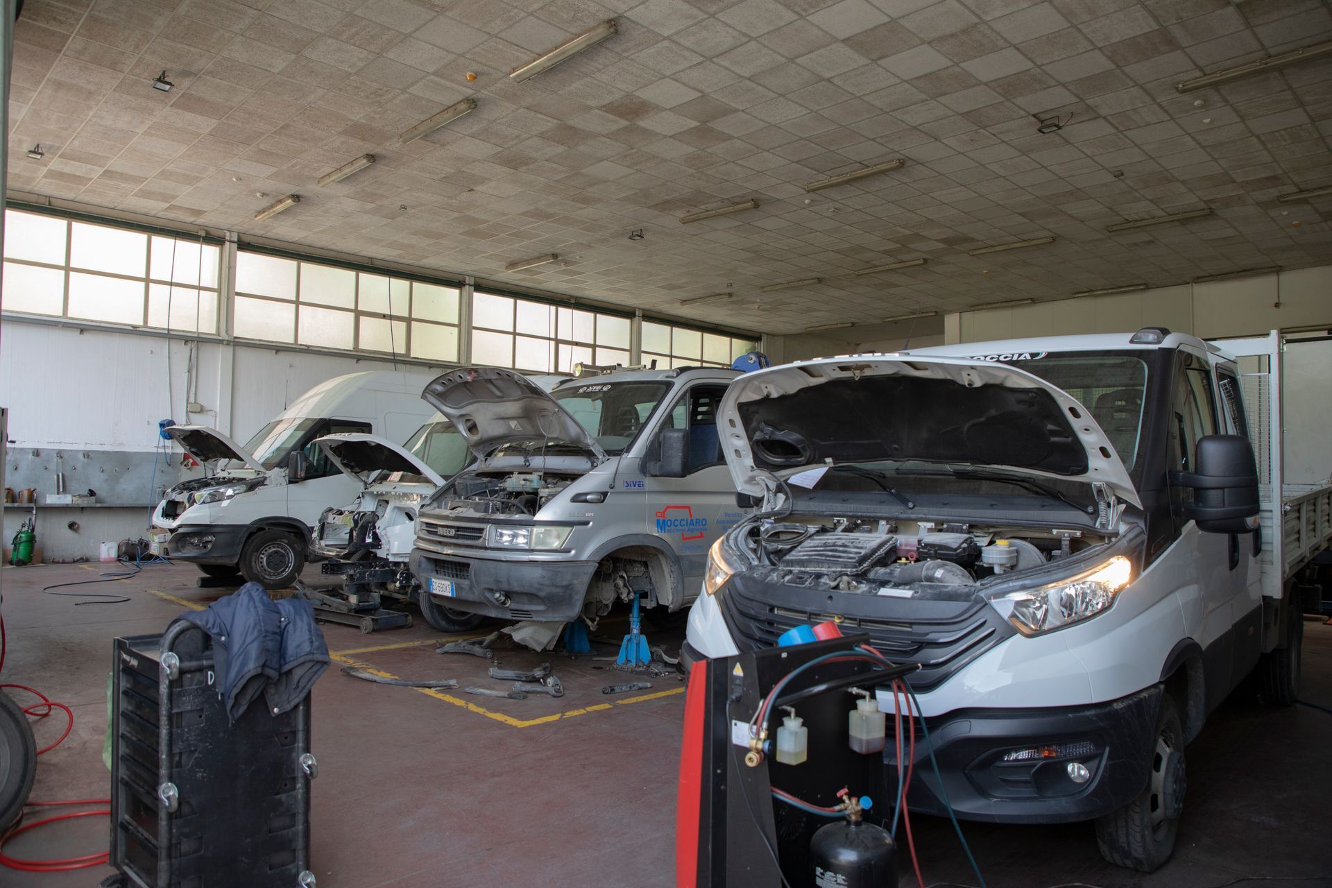 Veicoli con cofani aperti all'interno di un garage. Officina di riparazione auto.
