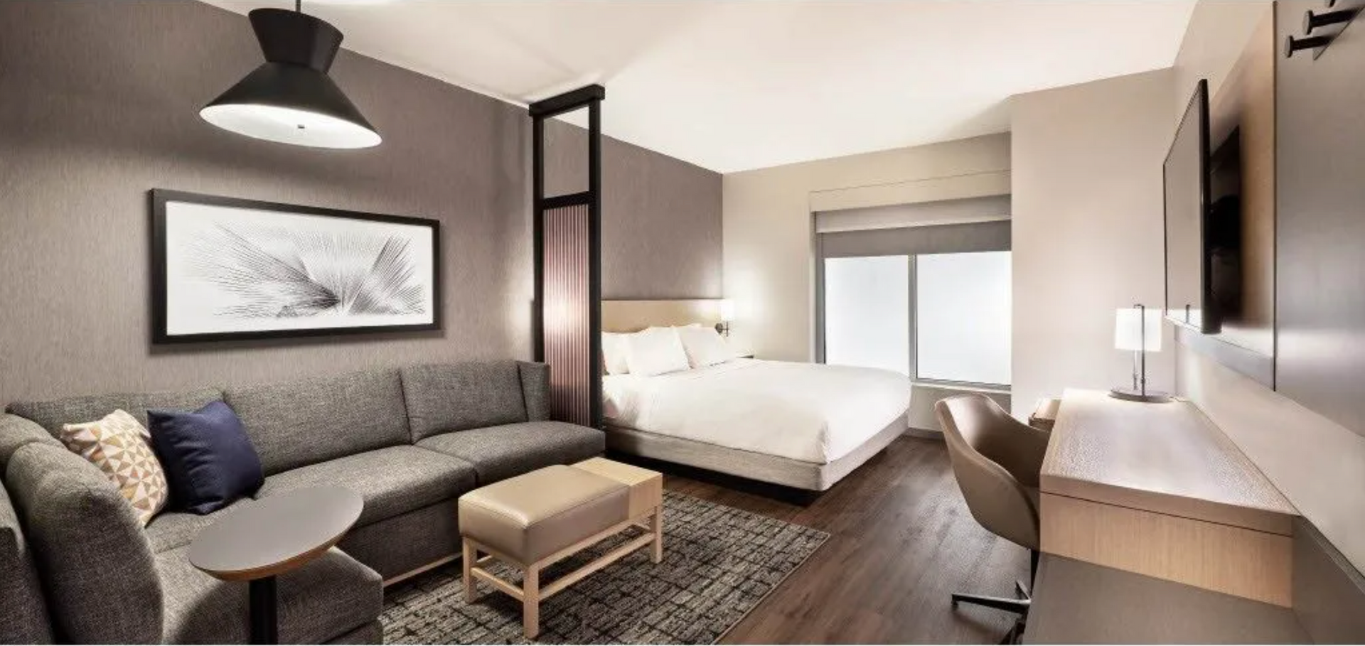 A hotel room with a king size bed , couch , desk and television.