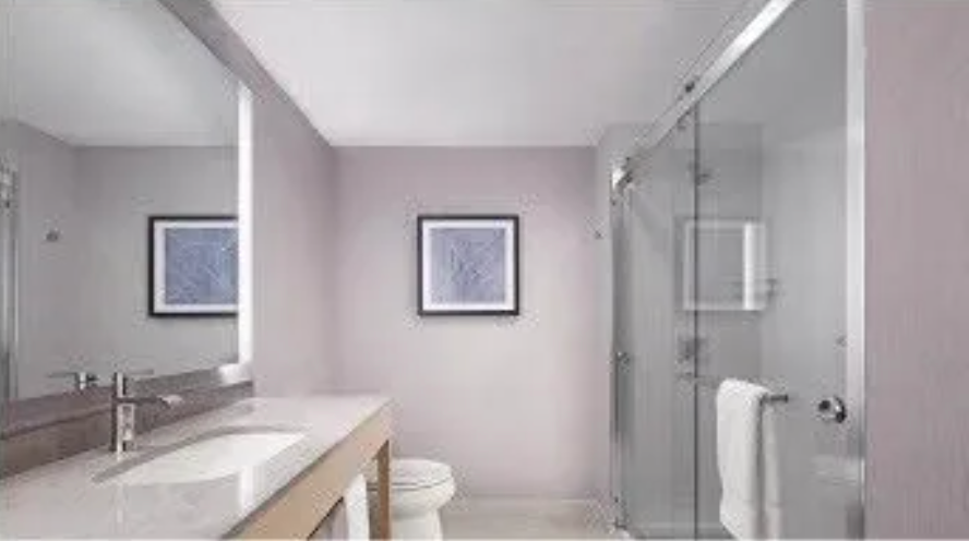A bathroom with a toilet , sink , mirror and shower stall.