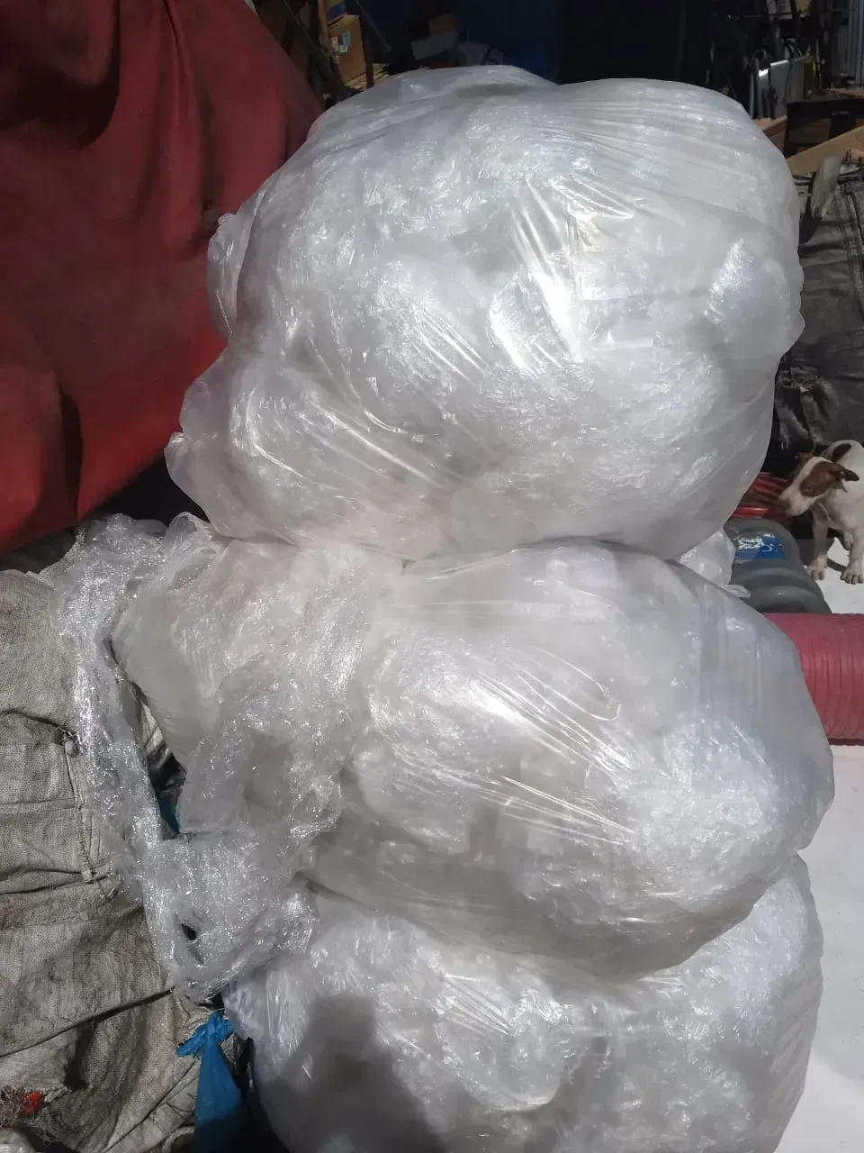 Montones apilados de bolsas de plástico transparente en el suelo, junto a una tela roja.