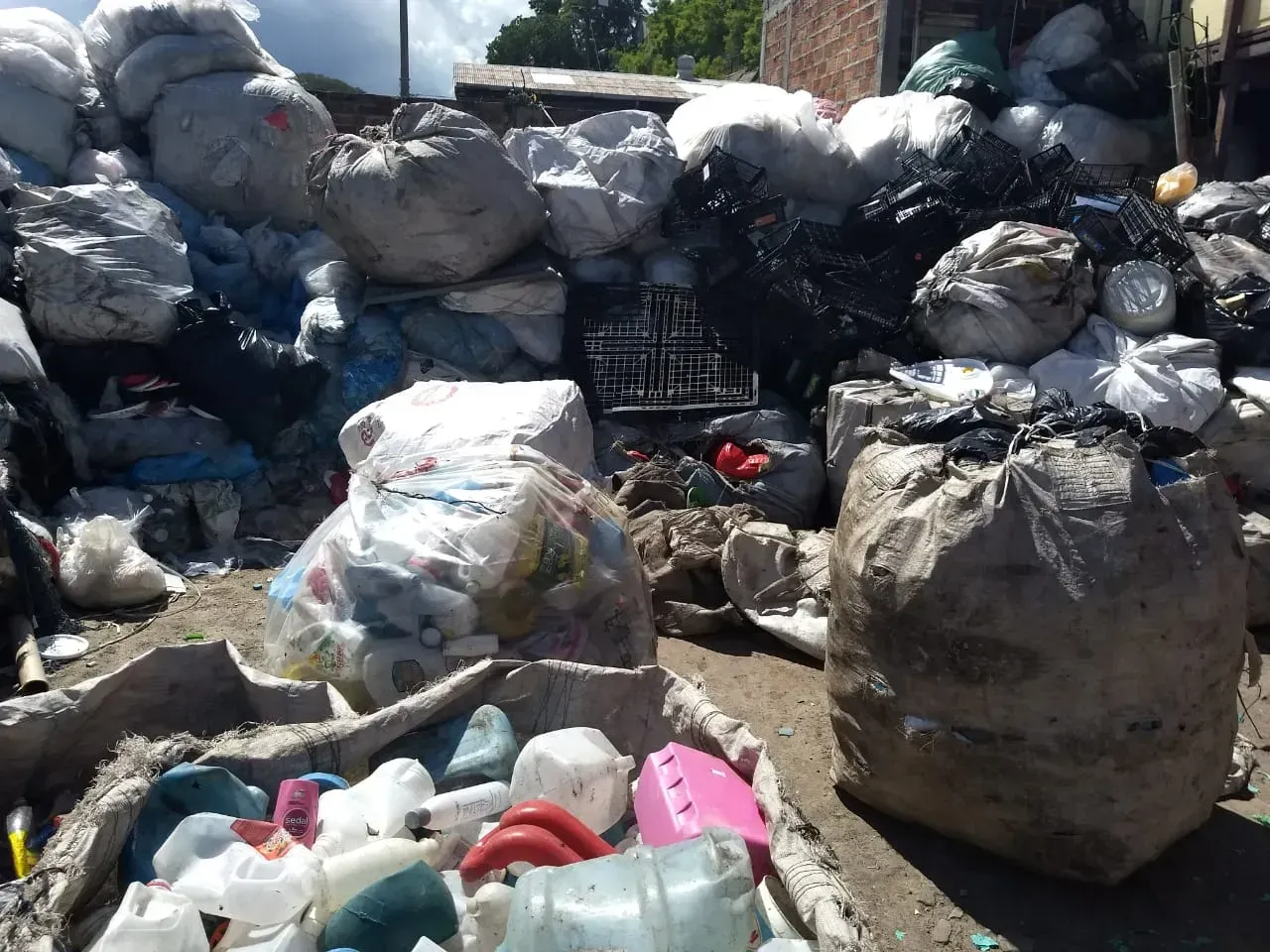 Grandes montones de residuos plásticos y bolsas de basura apilados al aire libre en una zona de reciclaje