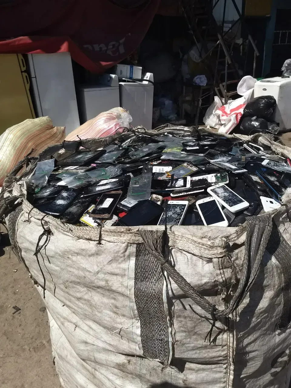 Un gran saco rebosante de teléfonos inteligentes usados en un desordenado trastero interior.