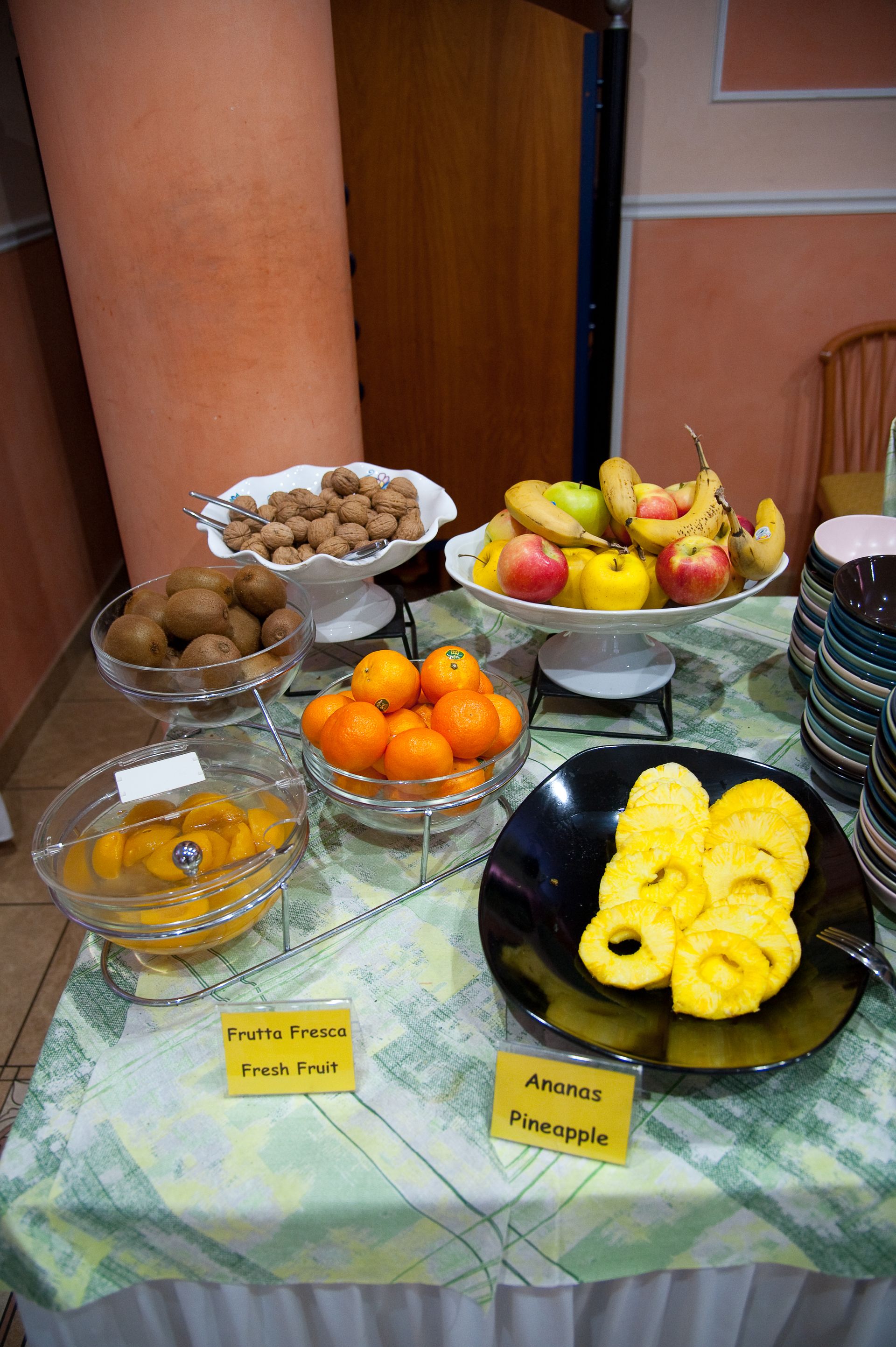 Buffet di frutta: in esposizione vari tipi di frutta, come arance, ananas, mele e kiwi.