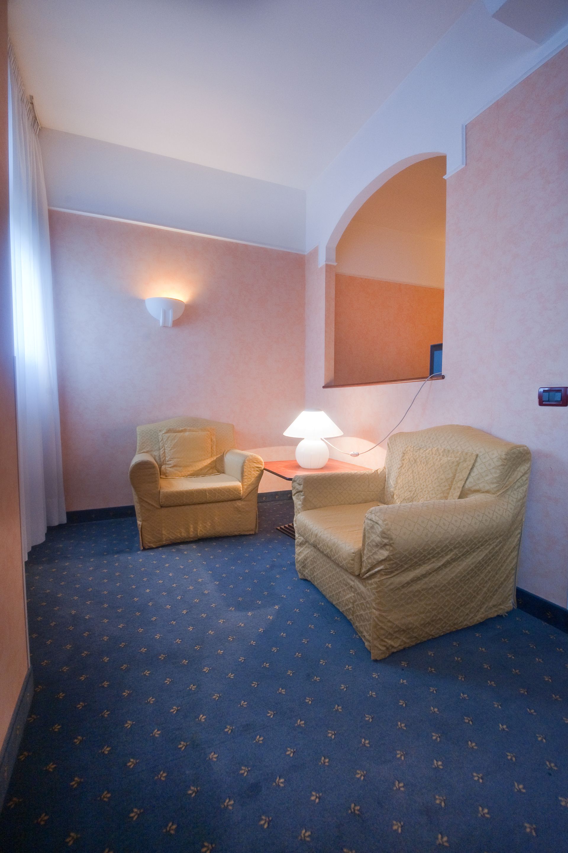 Due poltrone gialle sono disposte una di fronte all'altra in una stanza con un tappeto blu e pareti rosa.