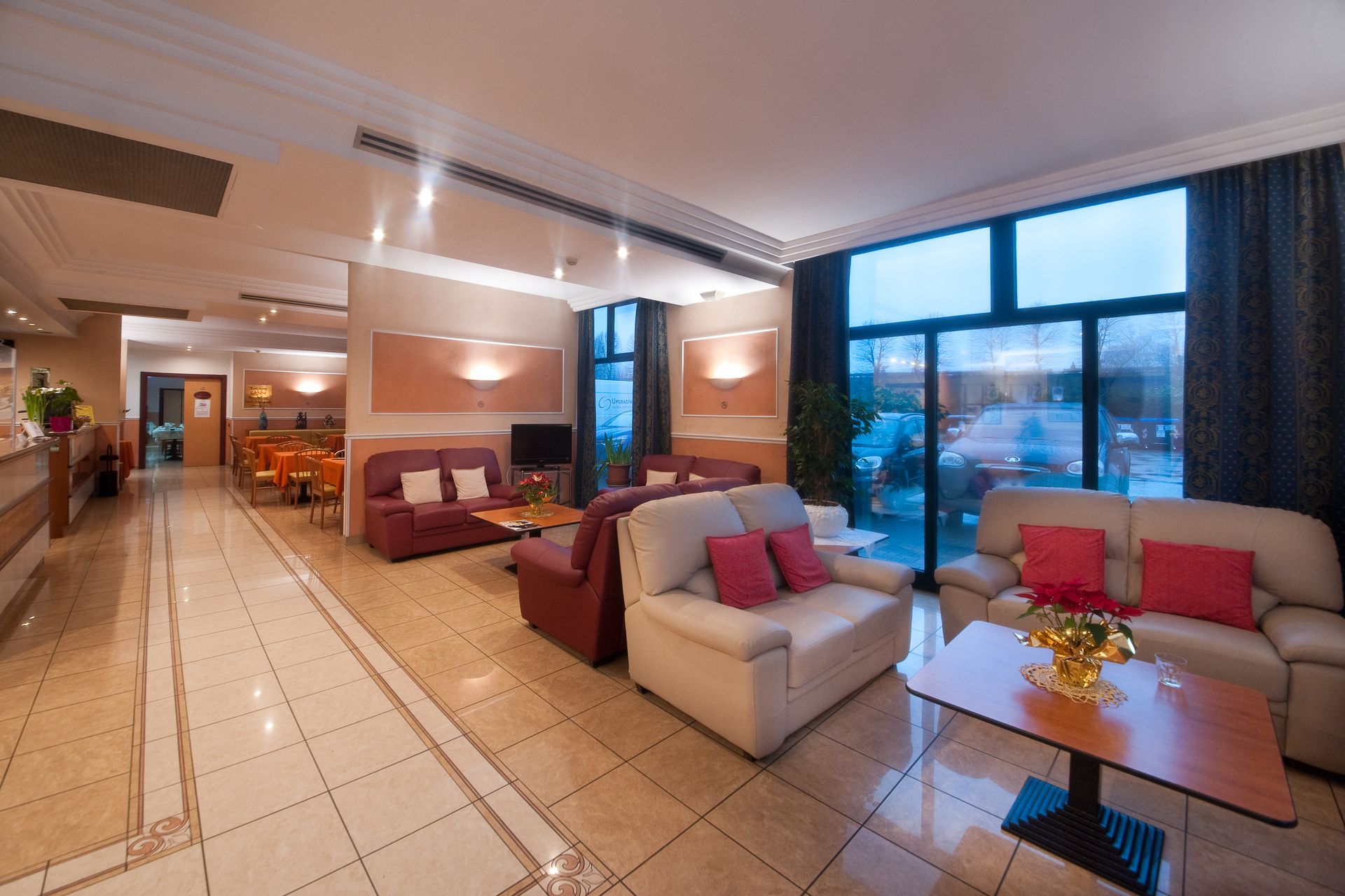 Hall dell'hotel con area salotto, ampie finestre e reception.