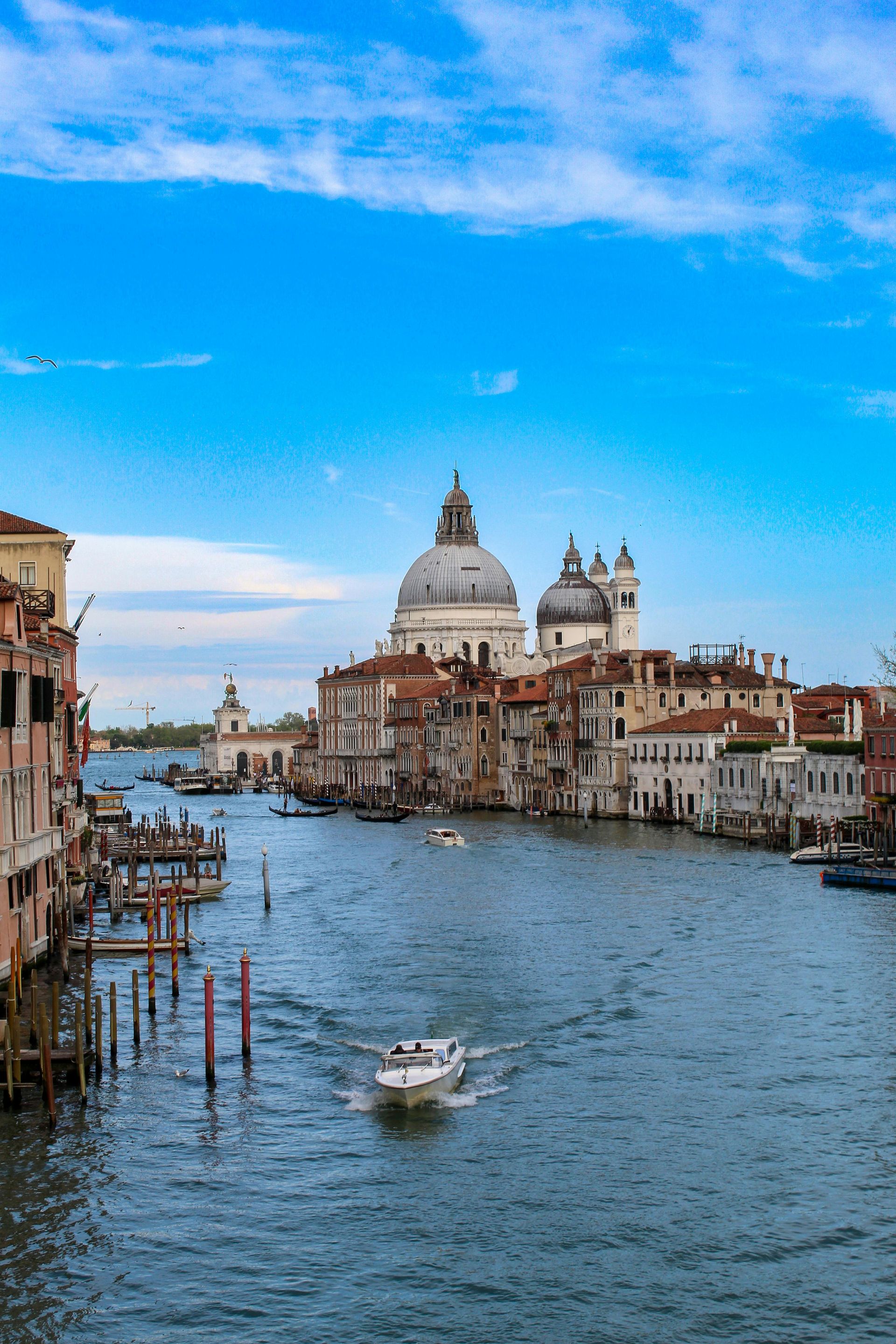 Blick auf die Kanäle Venedigs mit Booten, Gebäuden am Wasser und blauem Himmel.