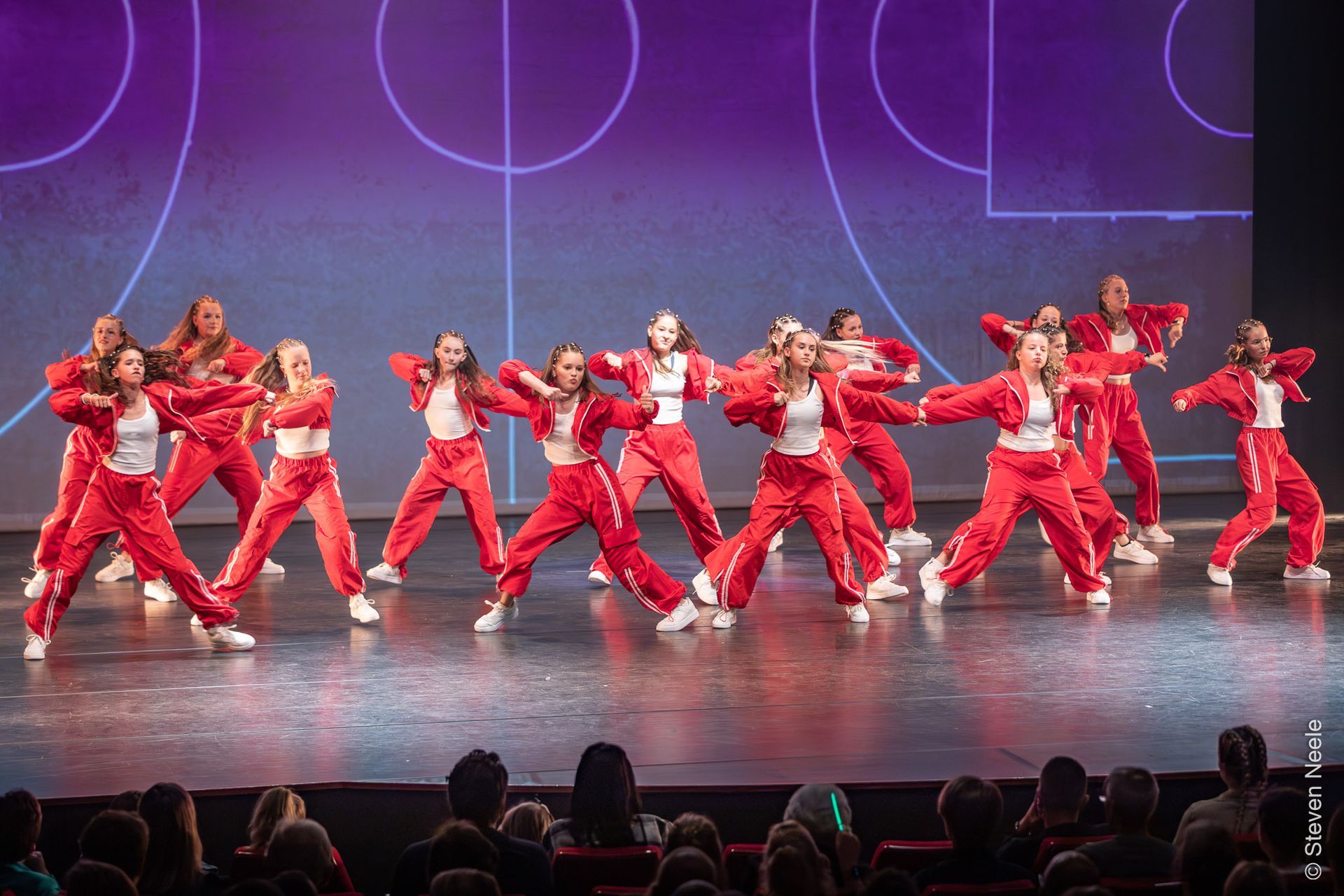 Een groep jonge vrouwen danst op een podium voor een publiek.