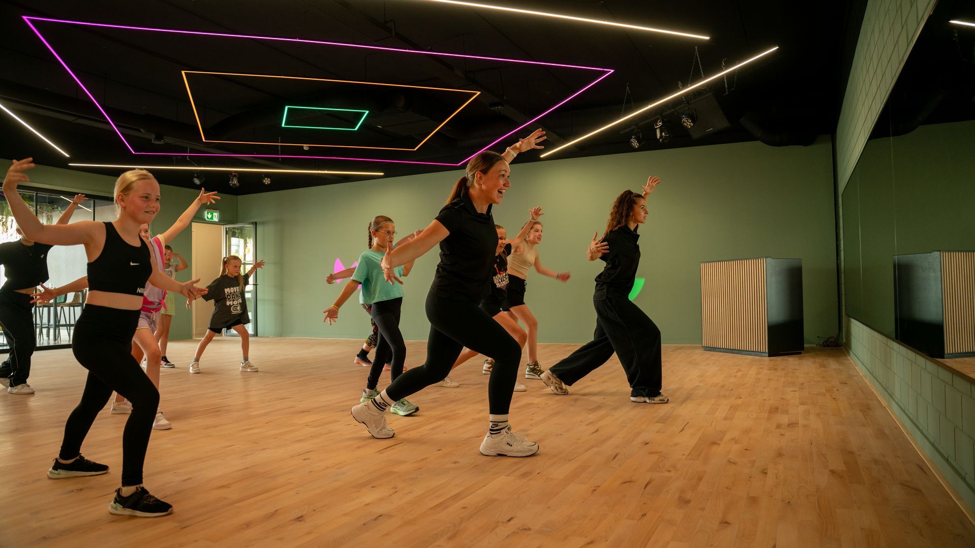 Een groep jonge vrouwen danst op een podium voor een publiek.