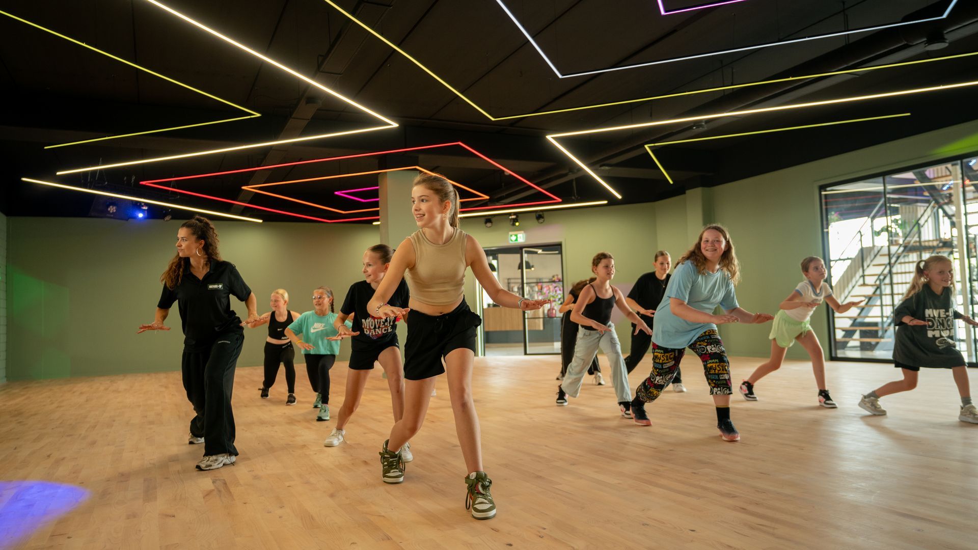 Een groep jonge kinderen danst op een podium.