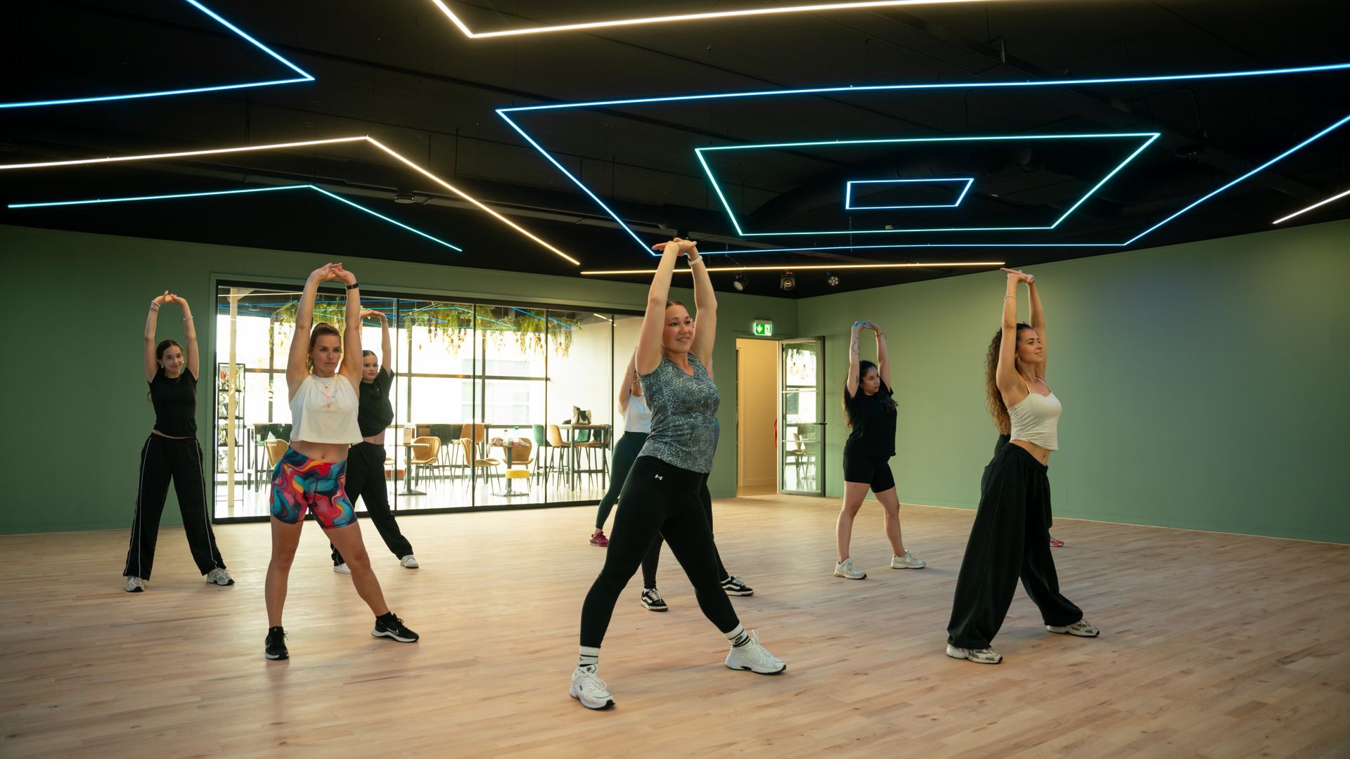 Een groep mensen doet squats op rode matten in een sportschool.