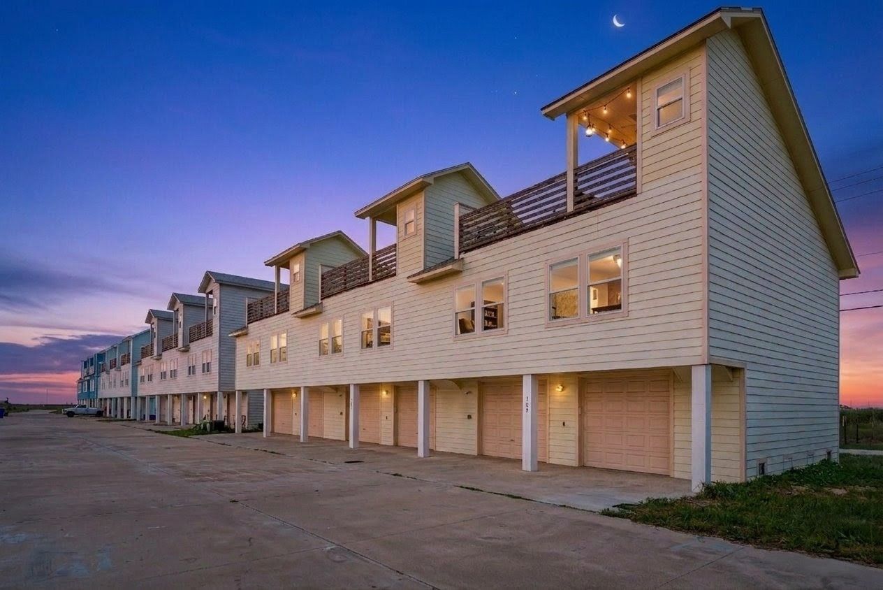 Port A Luxe coastal townhomes at twilight, with balconies and garages