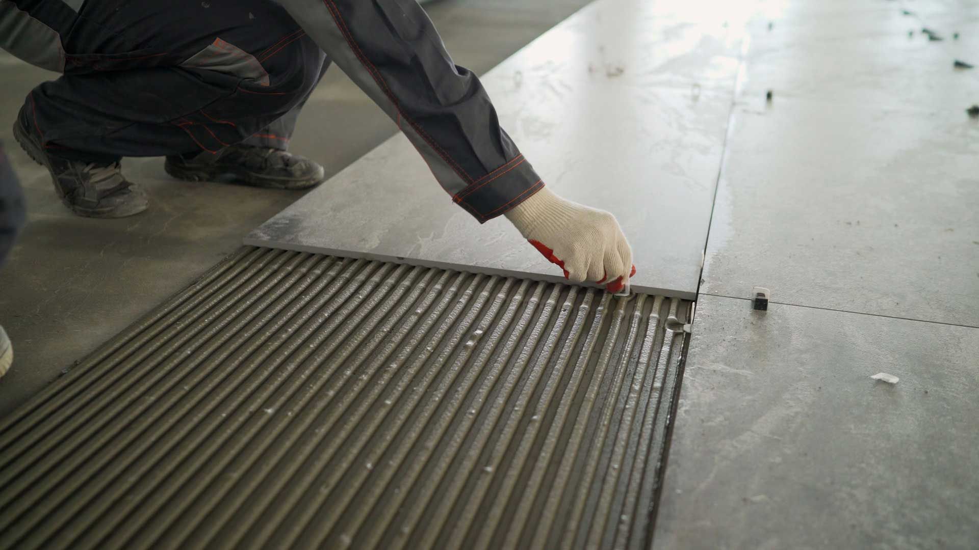 Worker spreading adhesive on a floor before laying tile or flooring panels