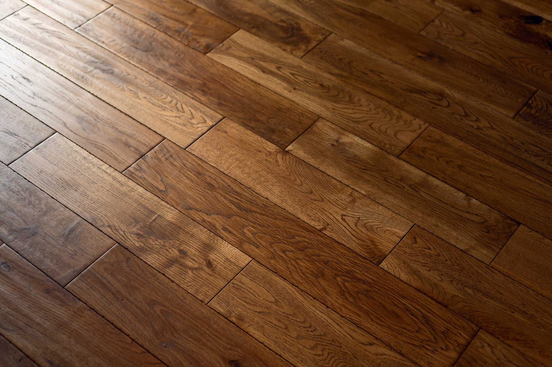 Close-up of warm-toned wooden floorboards with a glossy finish and diagonal grain patterns.