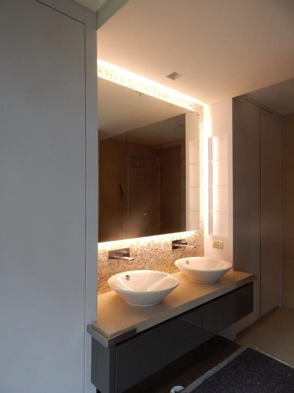 Doppio lavabo da bagno con specchio illuminato e piano in pietra.