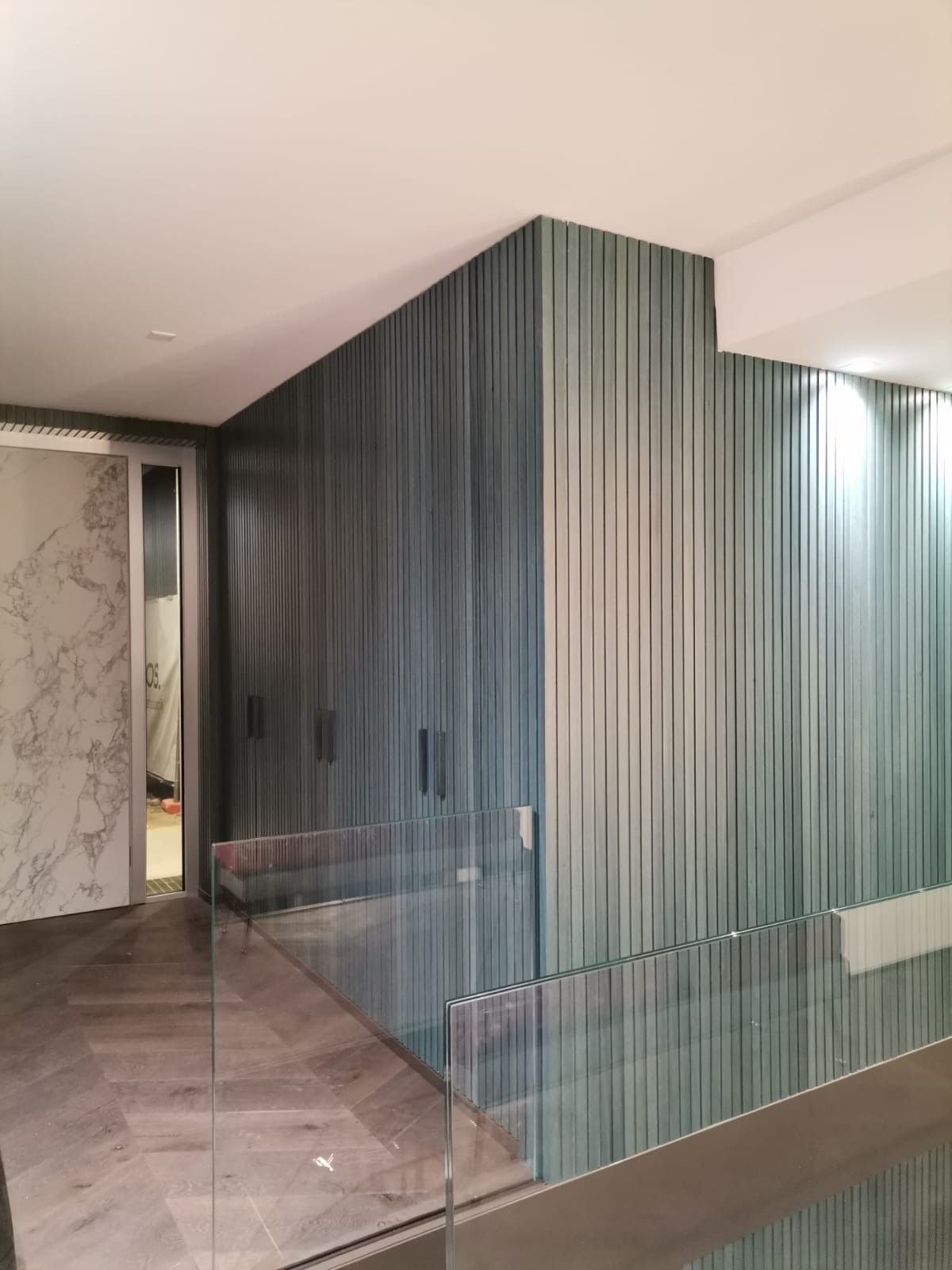 Corridoio interno moderno con parete divisoria in legno a righe.