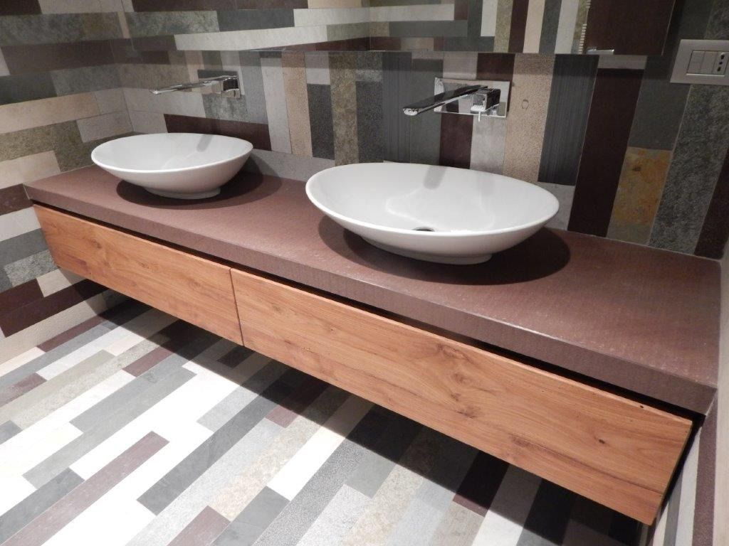 Lungo piano di lavoro in legno con rubinetto a parete e rivestimento piastrellato.