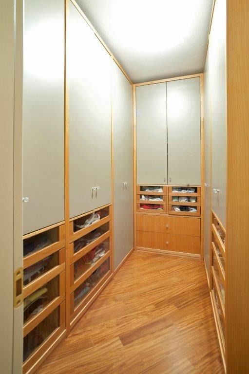 Cabina armadio stretta con scaffali a muro, finiture in legno chiaro.