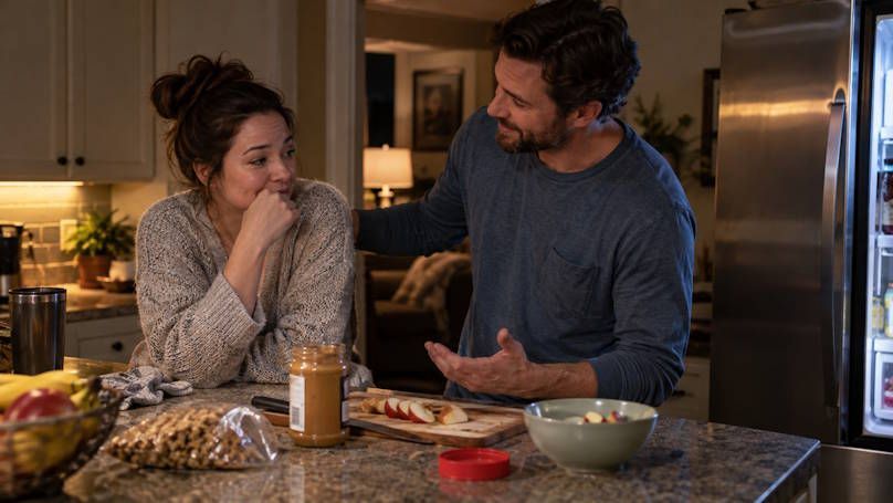 MIddle age couple up late at night in kitchen snacking and talking together