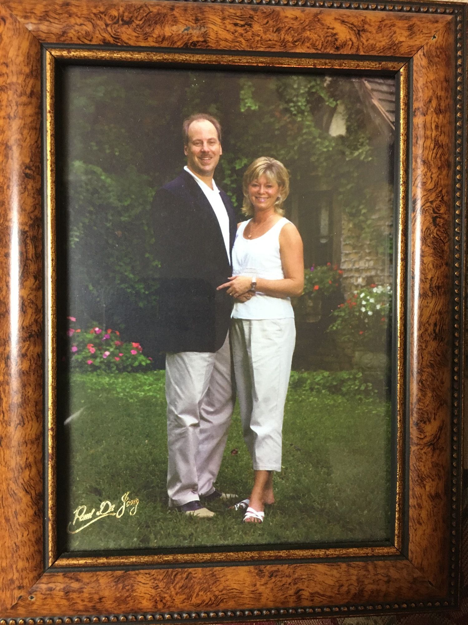 Framed portrait of a couple standing together outdoors in a garden.