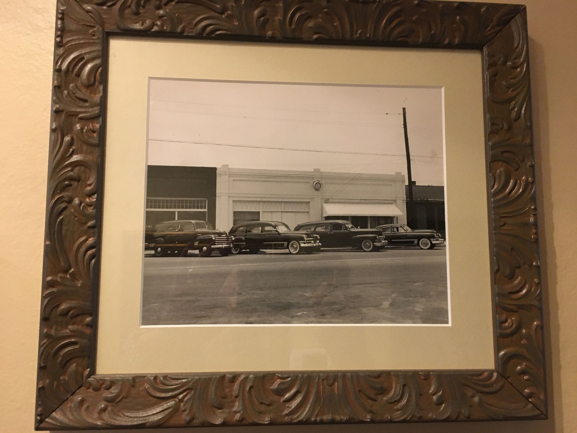 Framed black-and-white photo of classic cars parked outside a building.