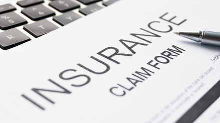 Claim Process Education Insurance claim form beside a laptop keyboard with a pen on it