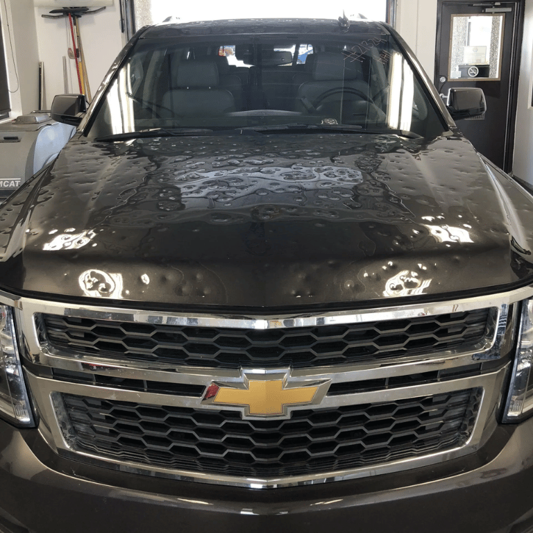 Black Chevrolet pickup truck parked indoors, front view with gold bowtie emblem.