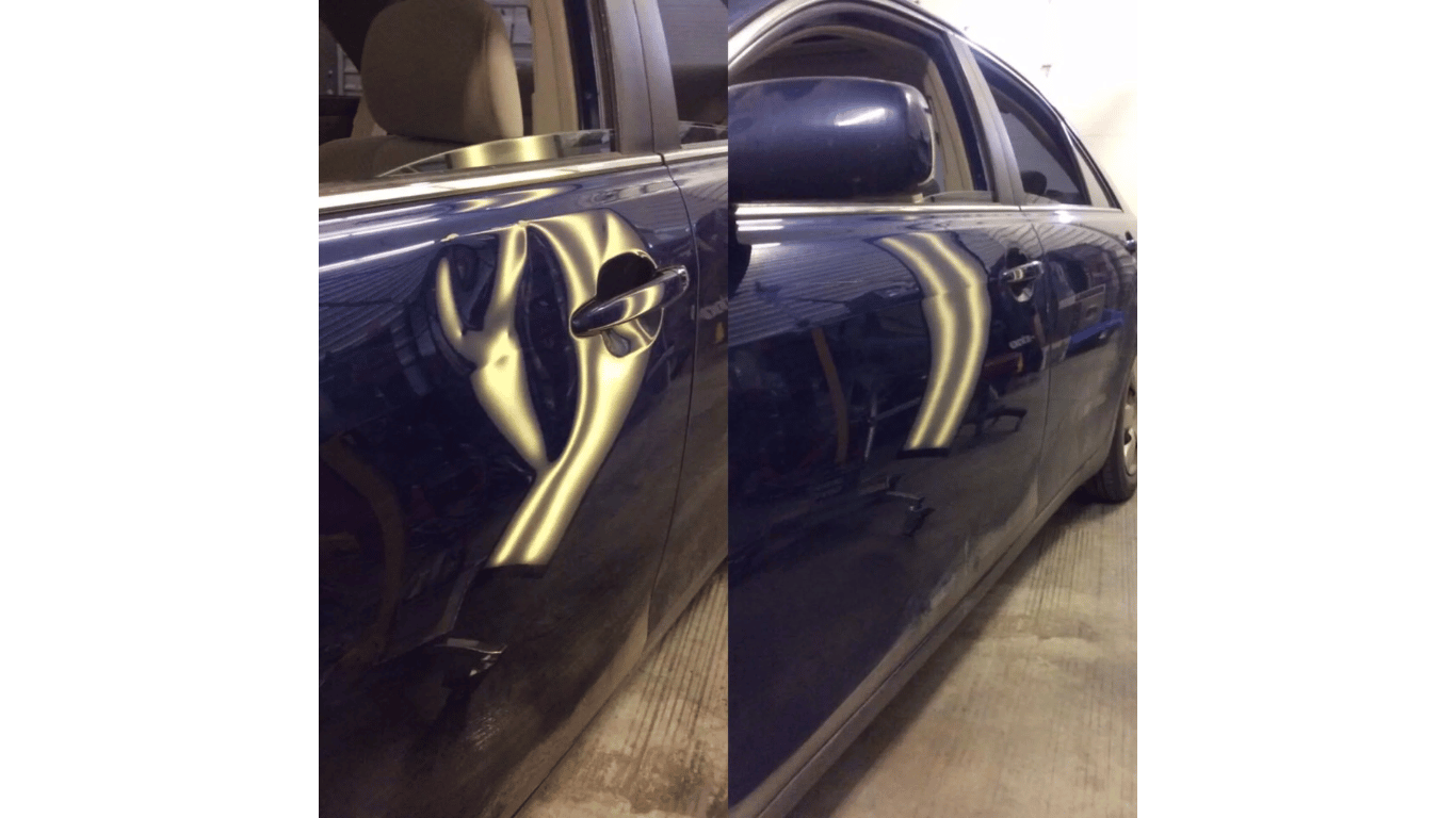 Dented blue car door with a large crumpled impact mark in a garage.