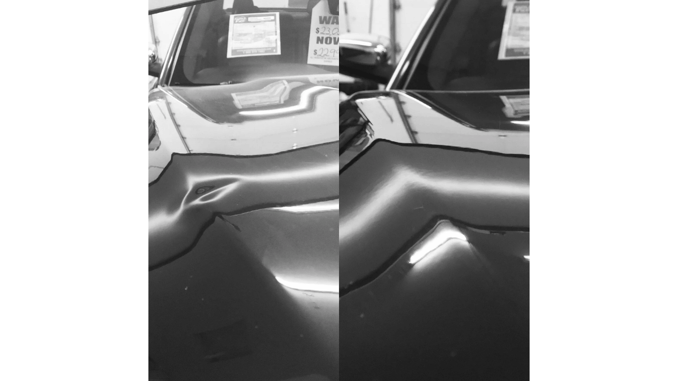 Shiny black car hood with wavy reflections, parked near a building and another vehicle