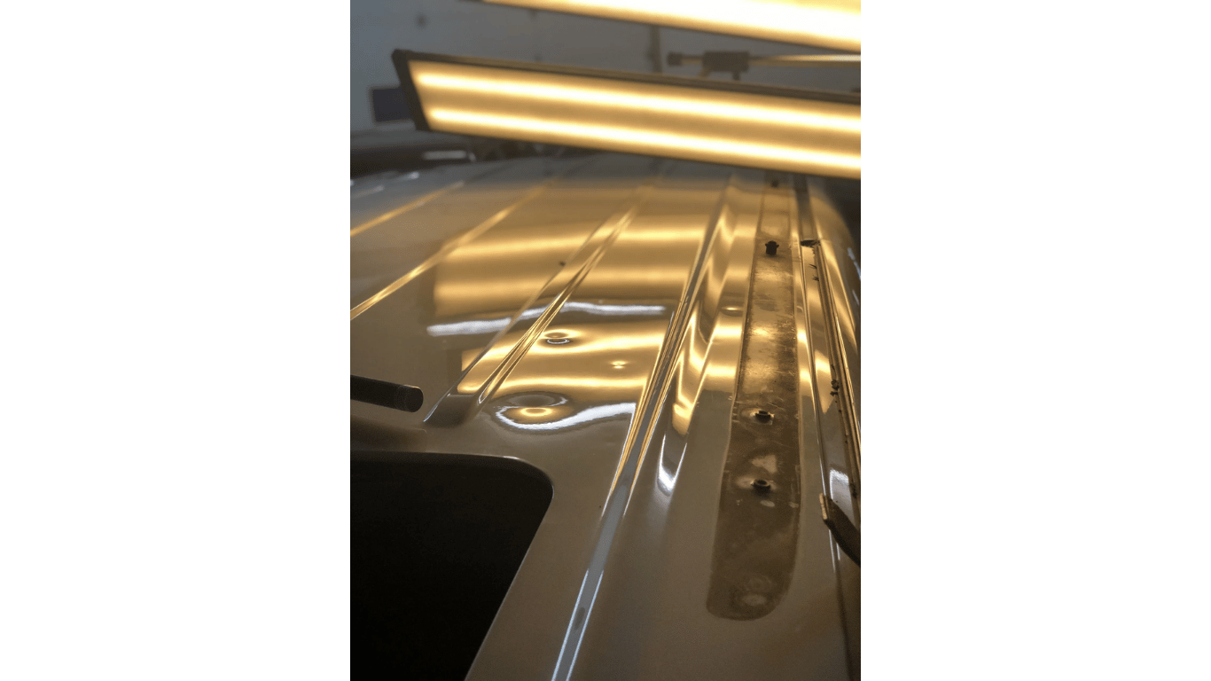 Close-up of a shiny gold car exterior reflecting overhead lights in a parking garage