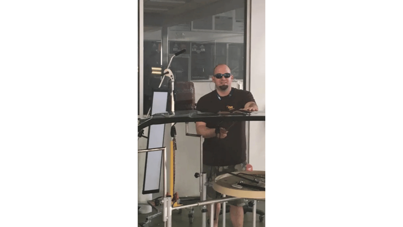 Man in sunglasses standing behind a railing in an indoor industrial setting