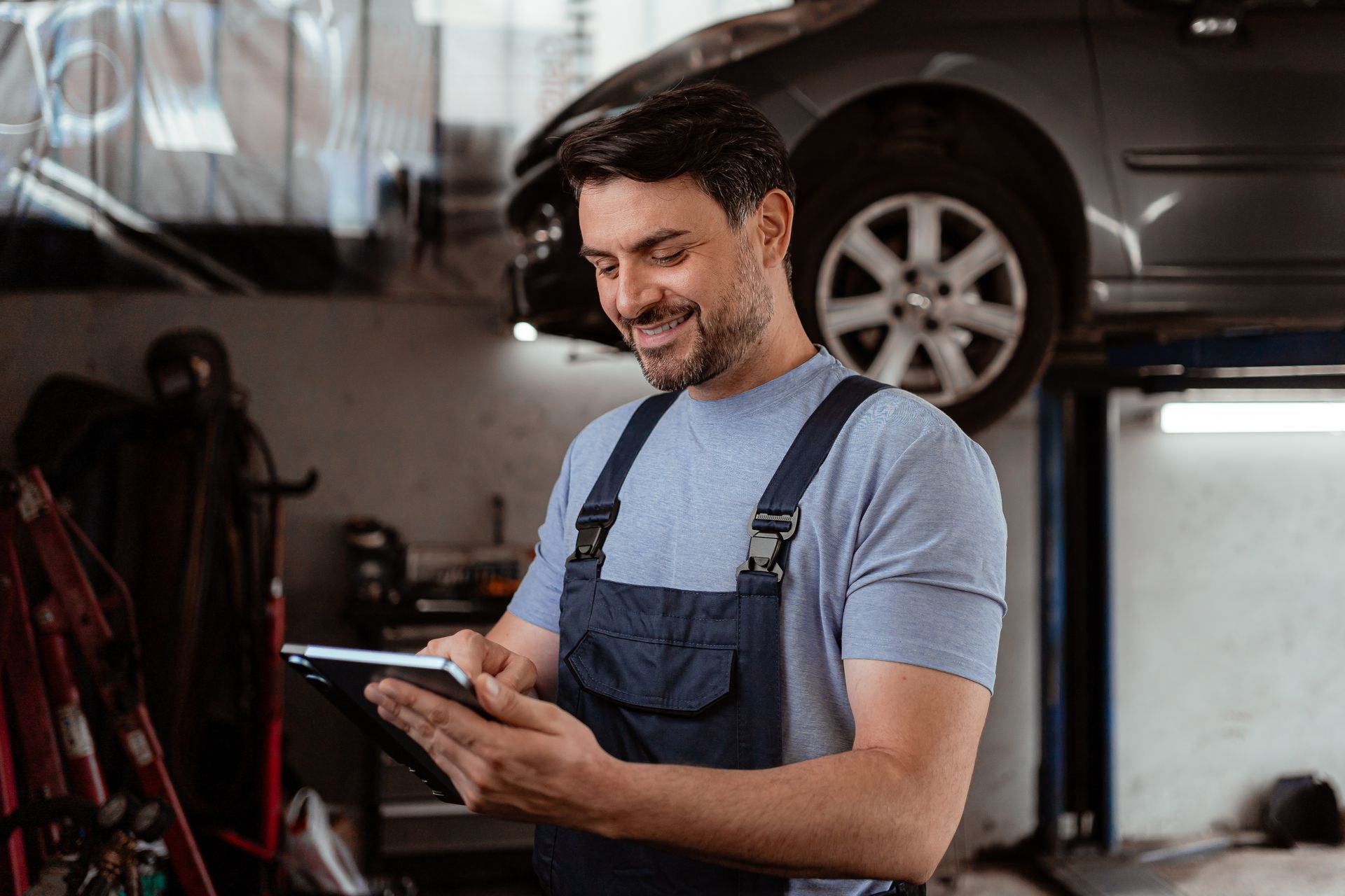 Man uses tablet to check car details in auto shop.