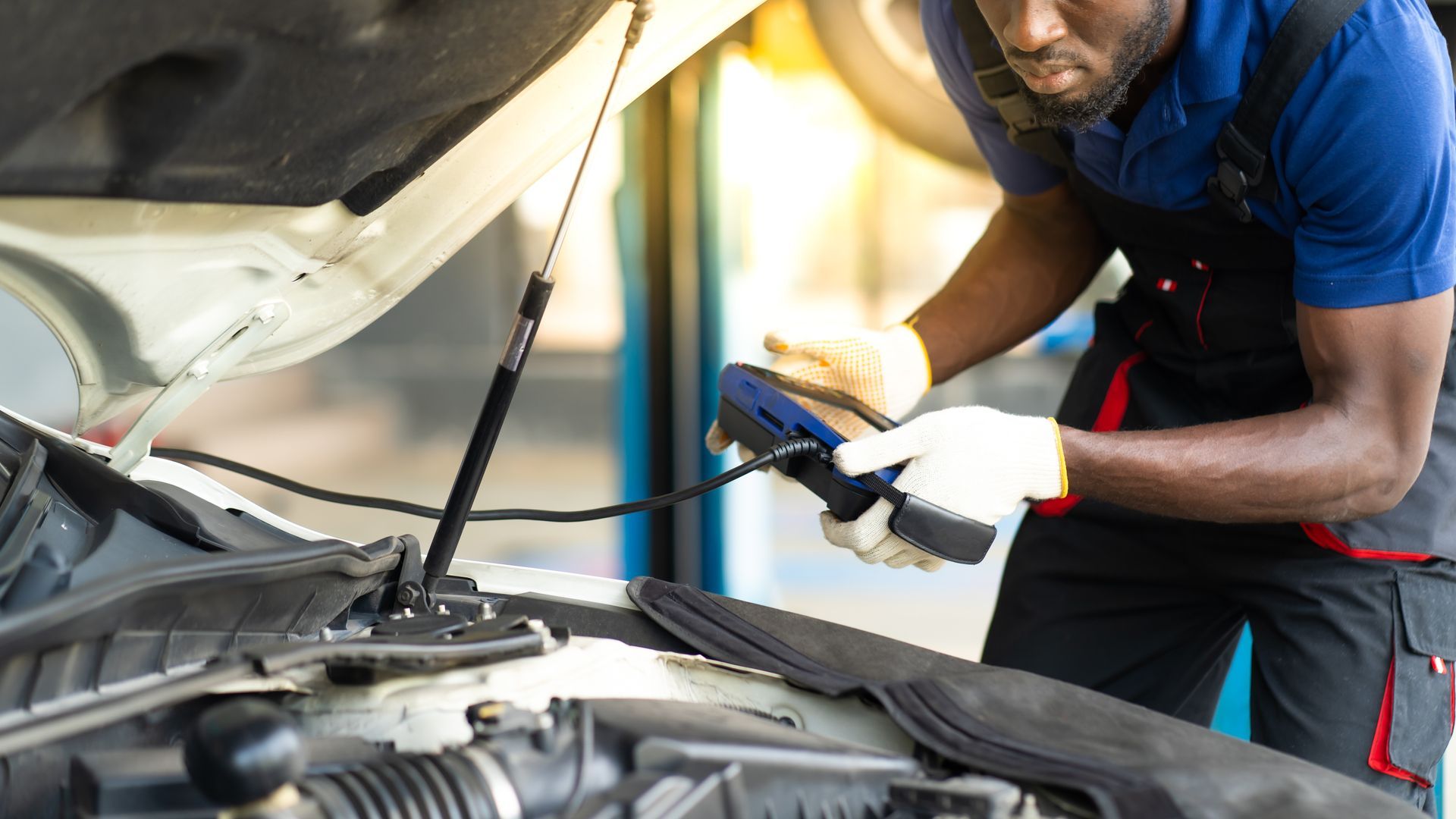 A close-up of a professional car mechanic checking a car engine by computer diagnostic software.