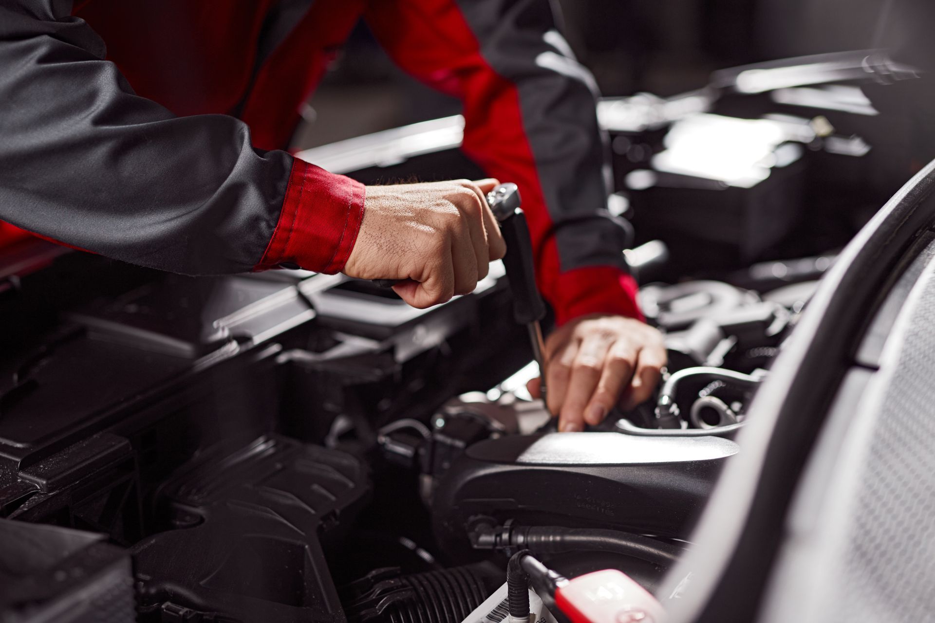 Close-up of technician using a wrench to repair a car engine, performing maintenance.