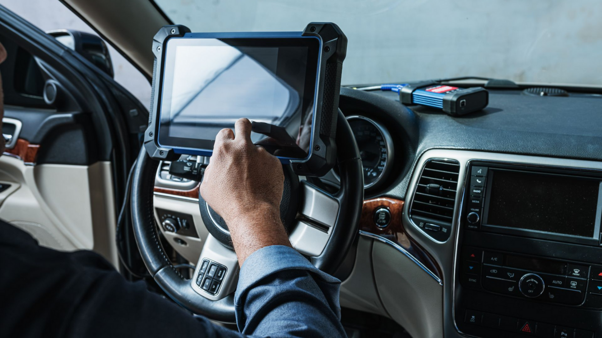 A close-up of a mechanic holding a digitizing device to a car wheel.