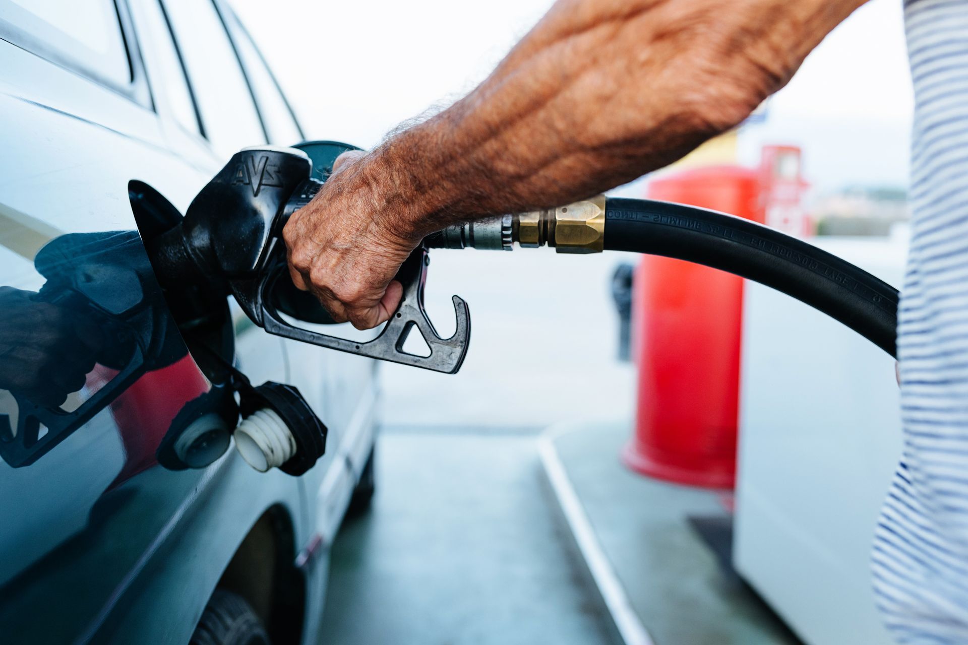 A man is pumping gas into a car at a gas station.