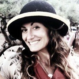A woman is wearing a hat and smiling for the camera.