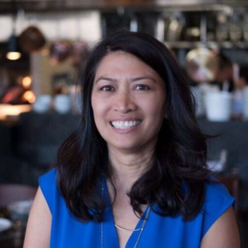 A woman in a blue shirt is smiling for the camera.
