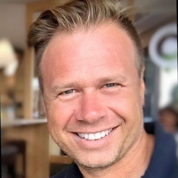 A man in a blue shirt is smiling for the camera.