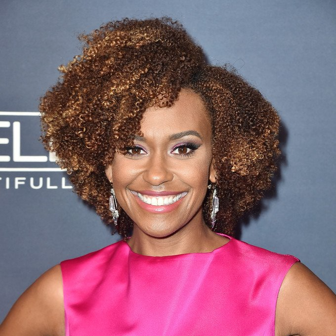 Actress Ryan Michelle Bathe in a pink dress is smiling in front of a sign that says beautiful