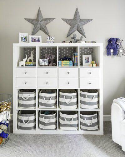 A white shelf with drawers and striped baskets in a room