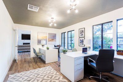 A room with a lot of windows and a desk with a laptop on it.