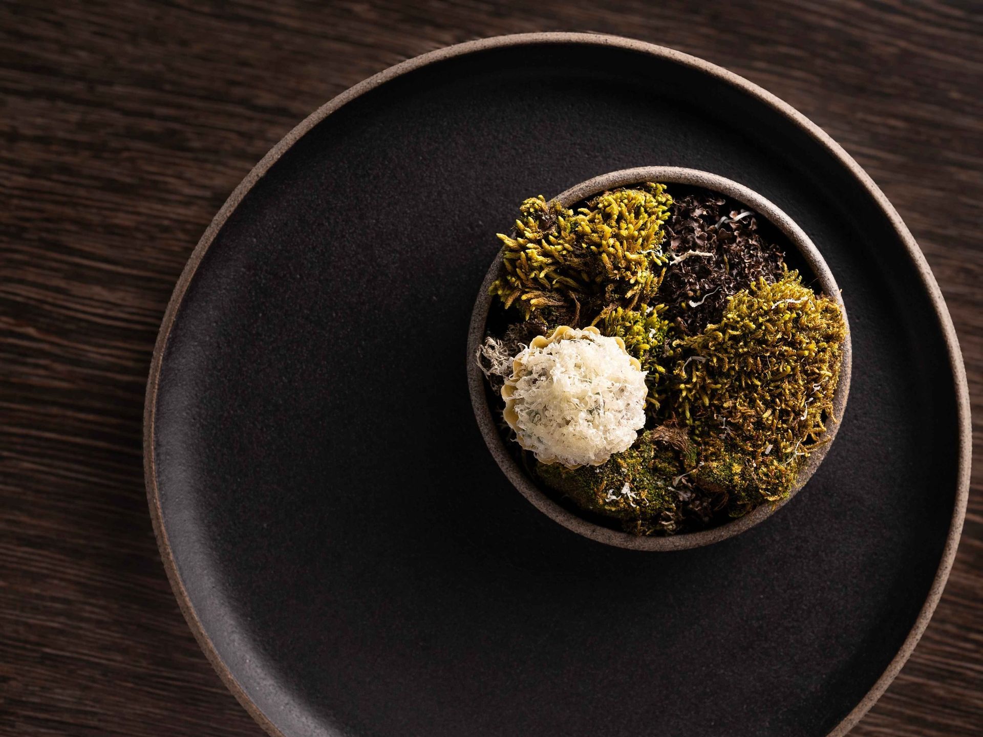 A black plate with a bowl of food on it