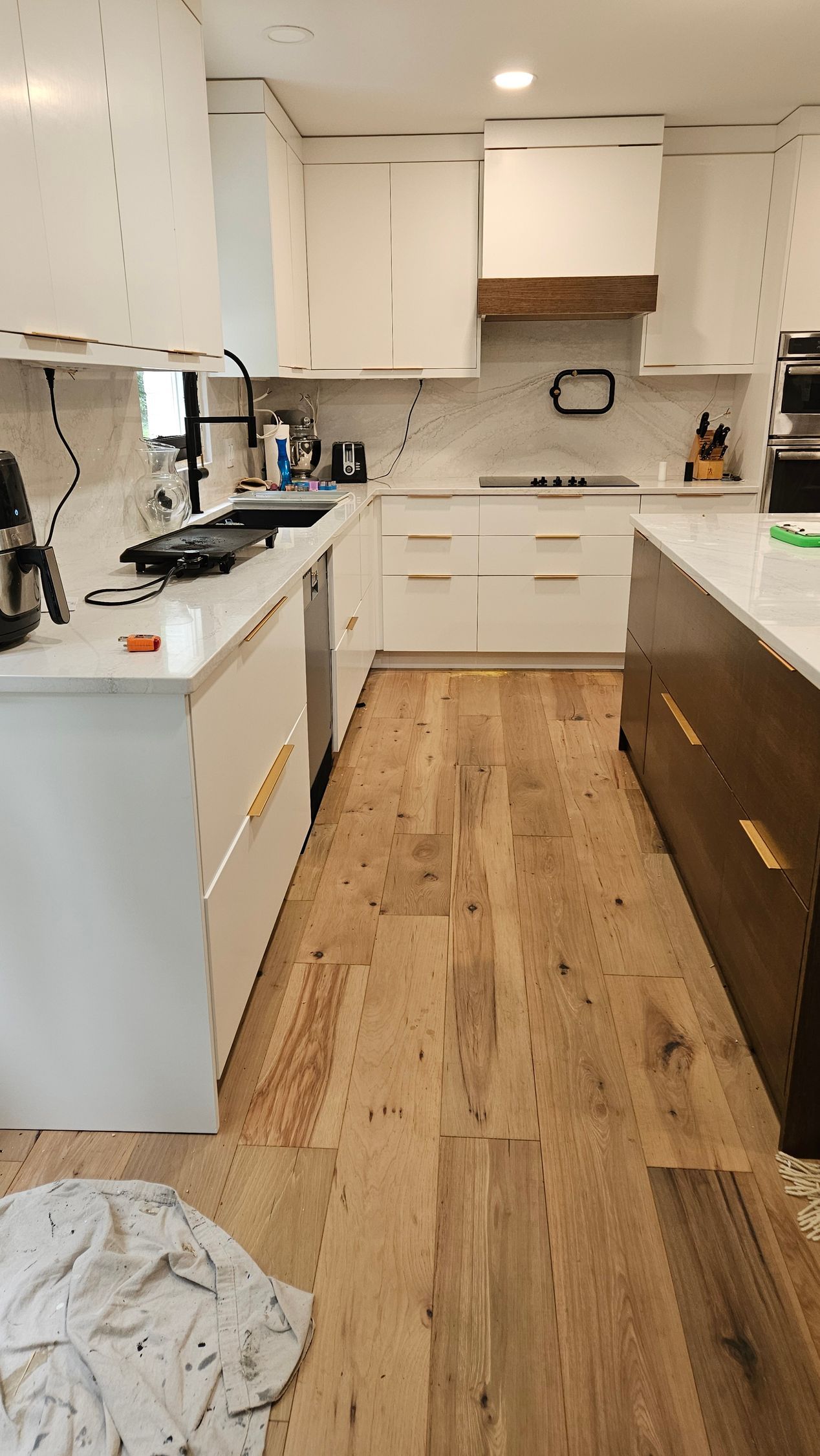 Modern kitchen with white cabinets, wood flooring, and a white island countertop